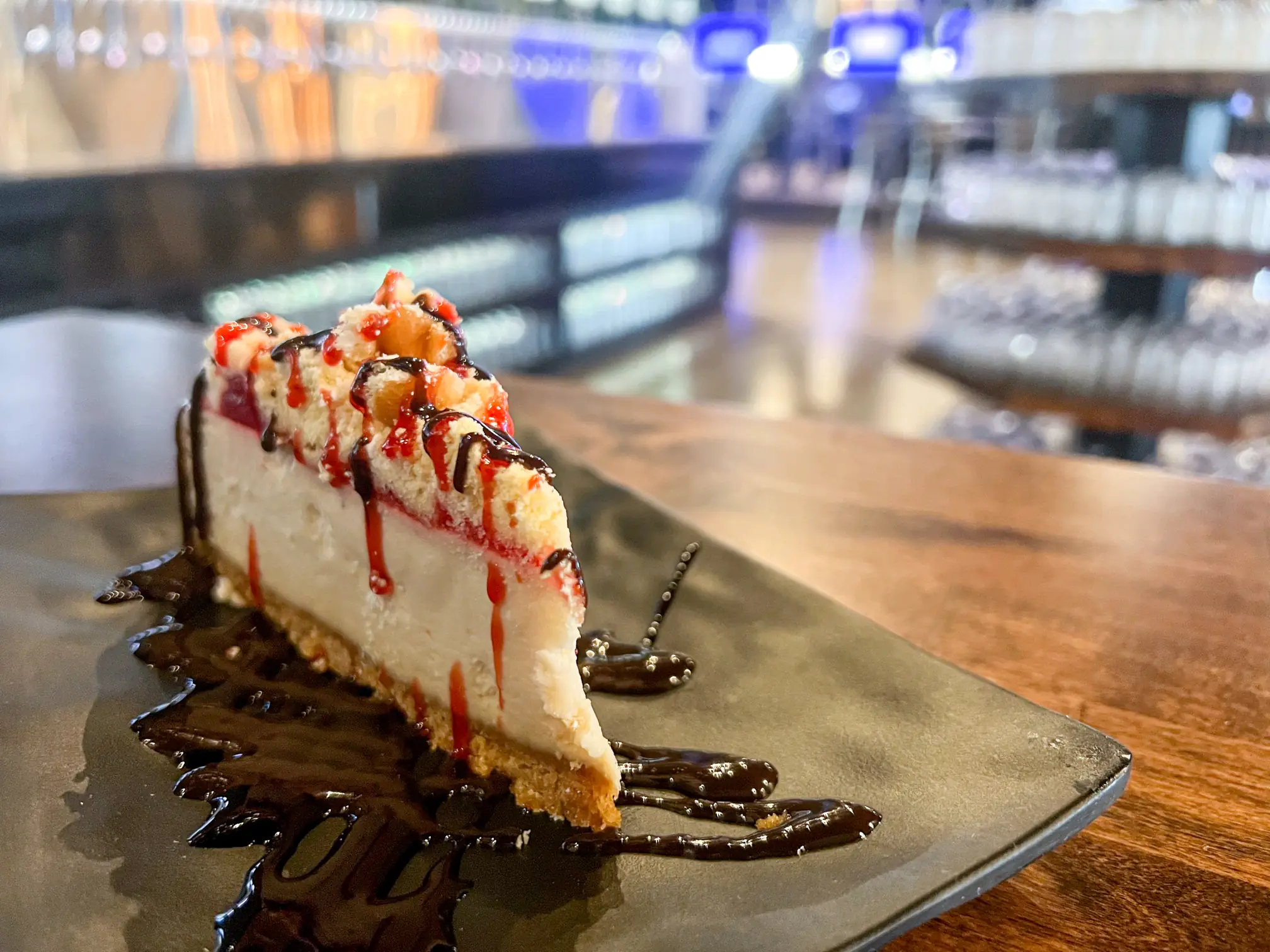 A slice of cheesecake drizzled with sauces.