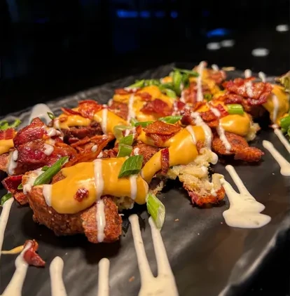 A plate of fried potato kegs smashed then covered with bacon, cheese, chives, and creme.